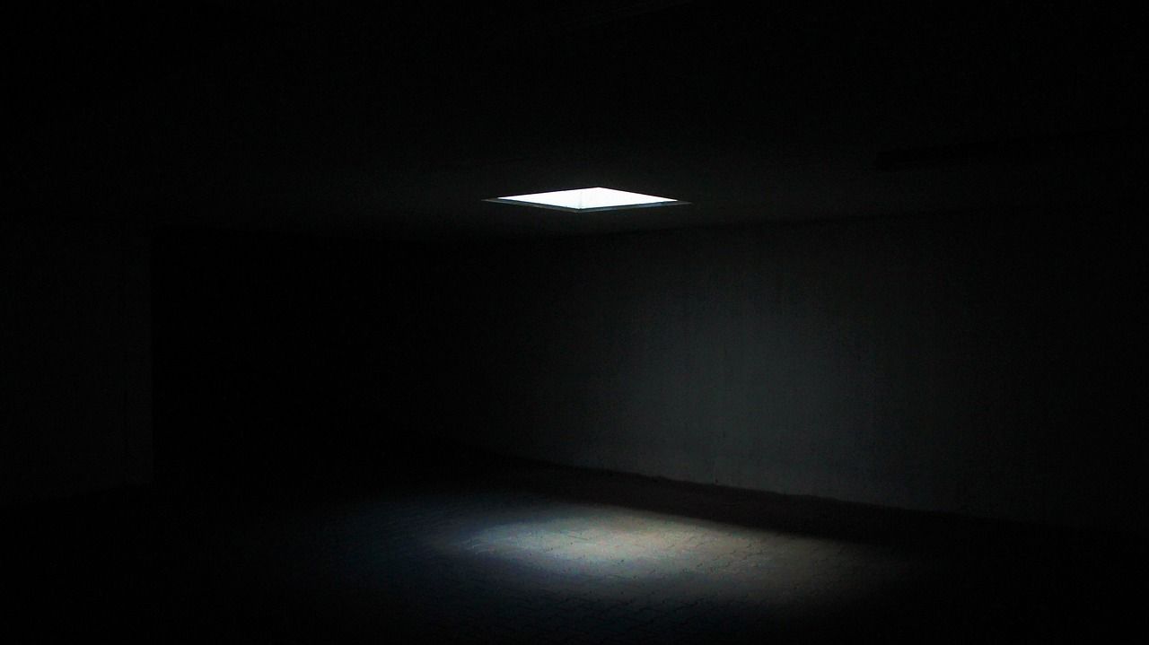 An empty dark room lit by a single square of light
