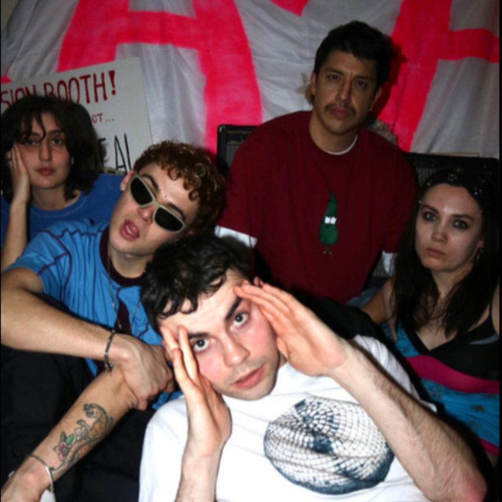Group shot of a young band crowded together in front of a pink and white banner