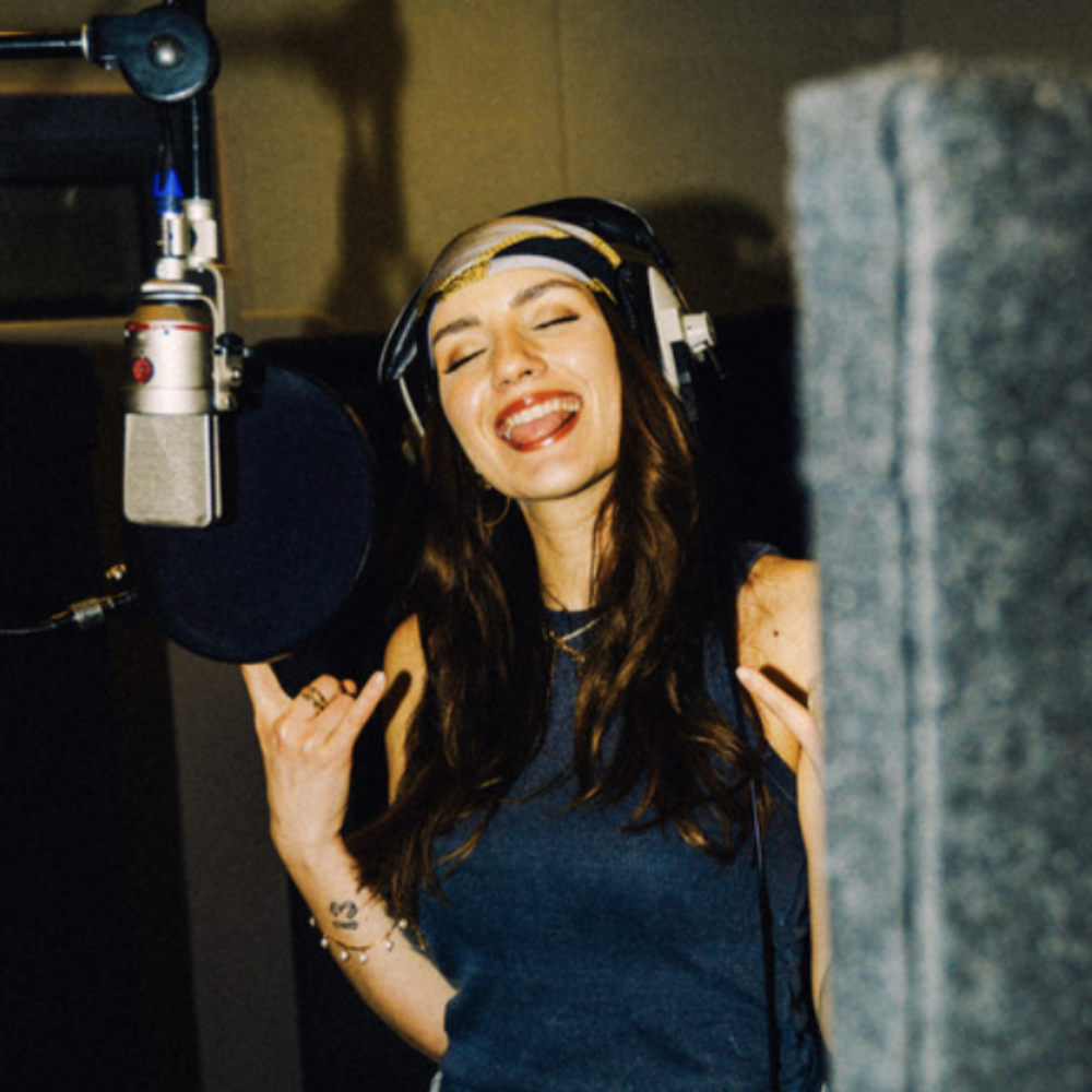Singer in headphones grinning at a studio microphone