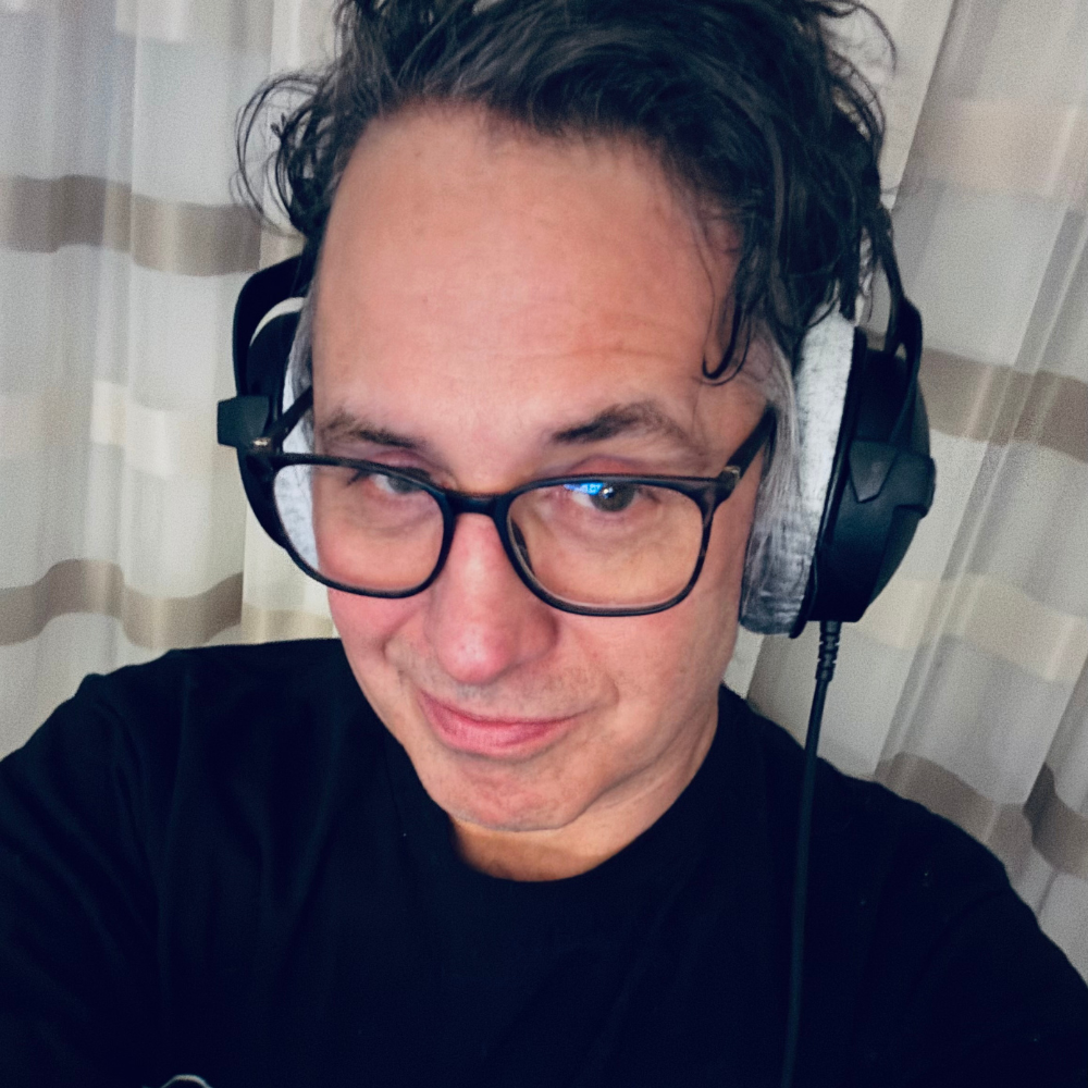 Man with glasses and headphones smiling at the camera