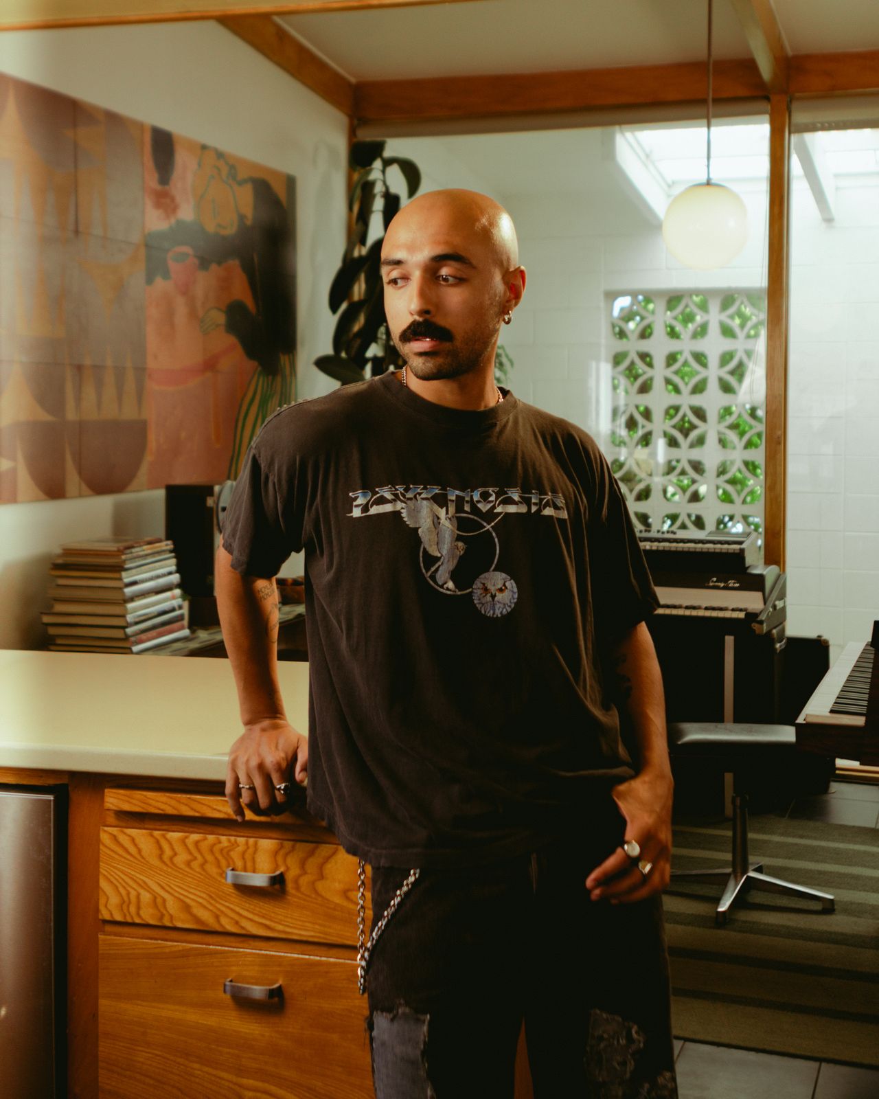 Deion Gill standing in a kitchen-style studio with art and plants behind him
