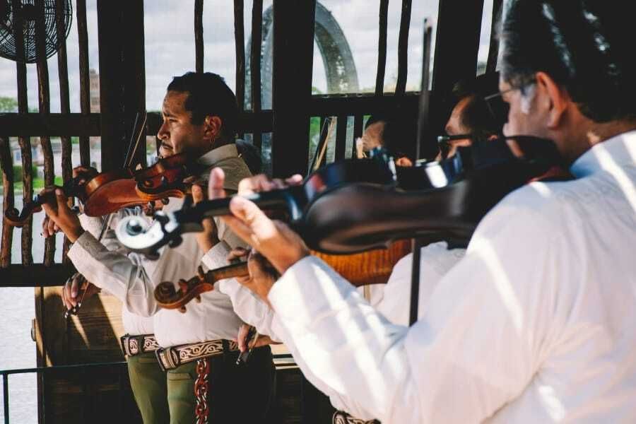 Mariachi violinists in white shirts performing, for the rise of regional Mexican music