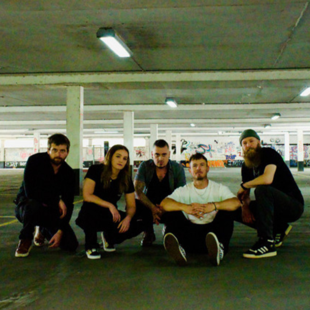 The 90s-rock band, five members crouching in an empty car park