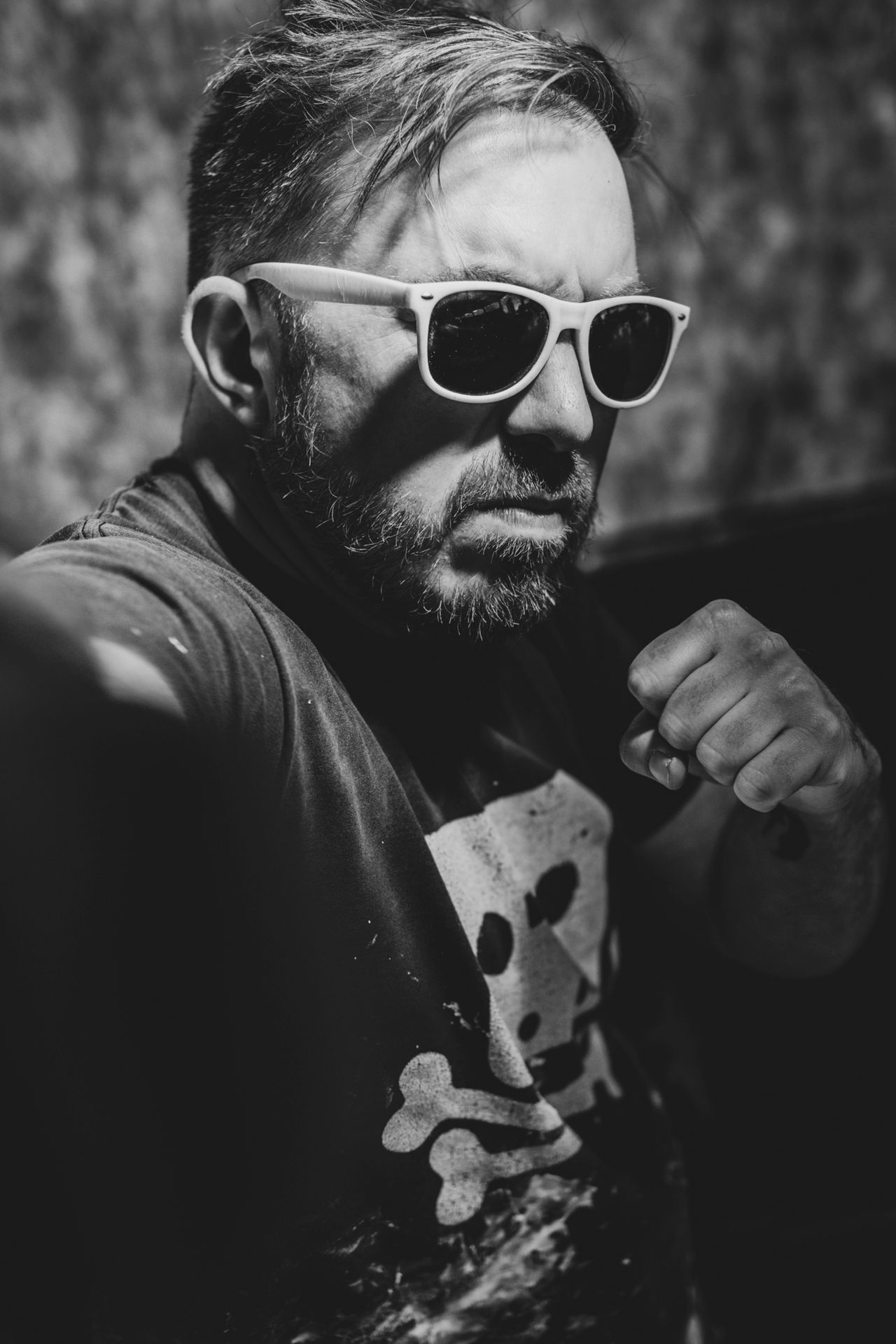 Lewca in white sunglasses and a skull T-shirt, raising a fist