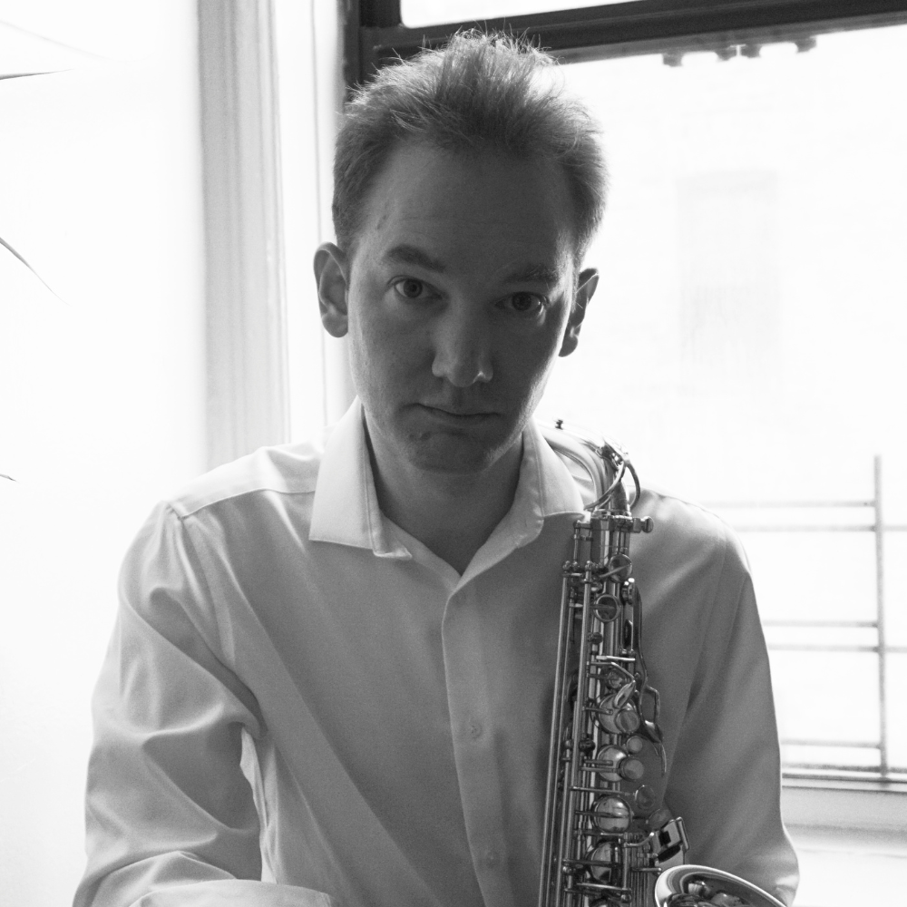 Saxophonist in a white shirt holding an alto sax, black and white