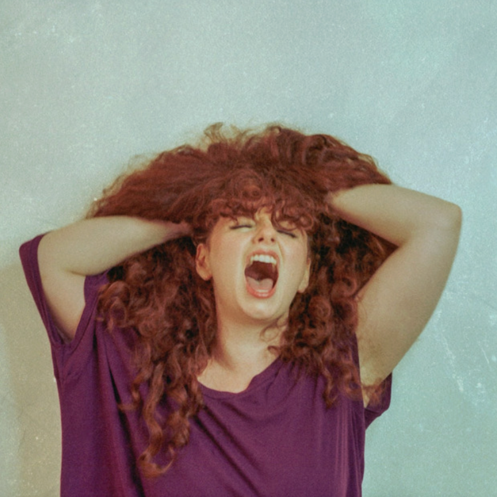 The ALT+POP+RAP pick screaming with her hands in a mass of curly red hair