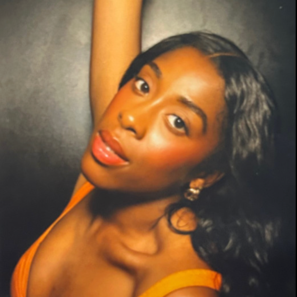 Cherece Richards in close-up, one arm raised, in warm light