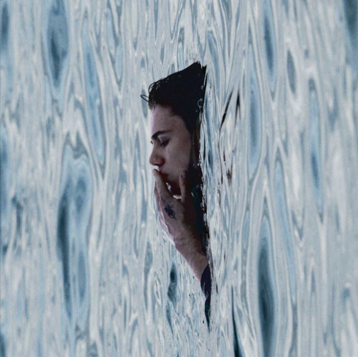 Album cover for The Kid LAROI's BEFORE I FORGET - his face pushing through a rippled blue surface