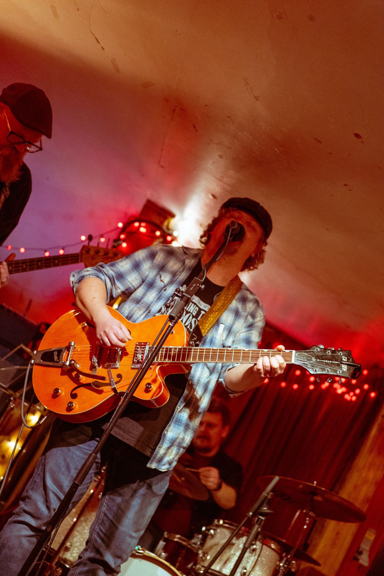 Miller Sessions live - a singer with a hollow-body guitar under red fairy lights