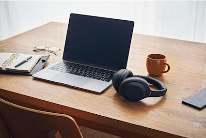 Sony WH-1000XM4 headphones on a desk beside a laptop and coffee mug