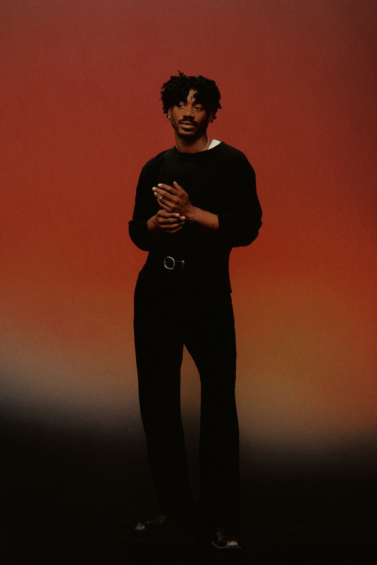 Bronze Avery standing in black against a red-orange backdrop