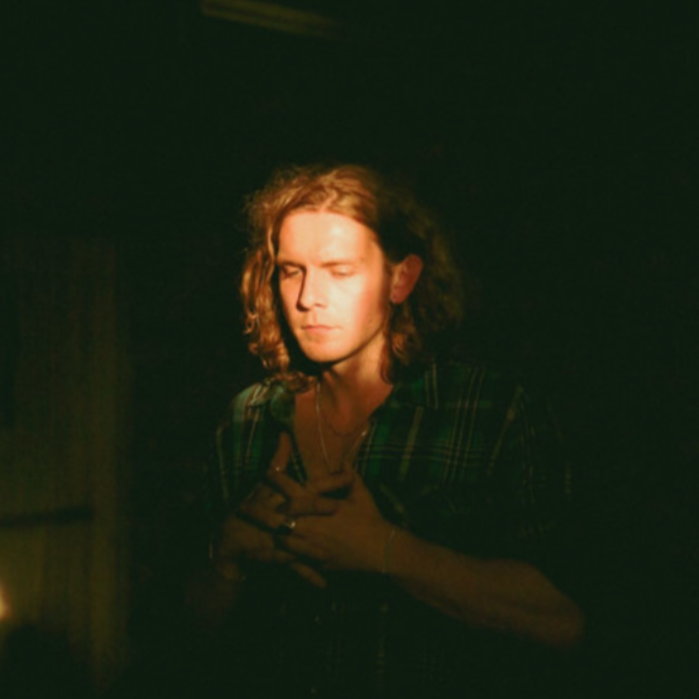 Lewis, eyes closed, hands on his chest in warm low light