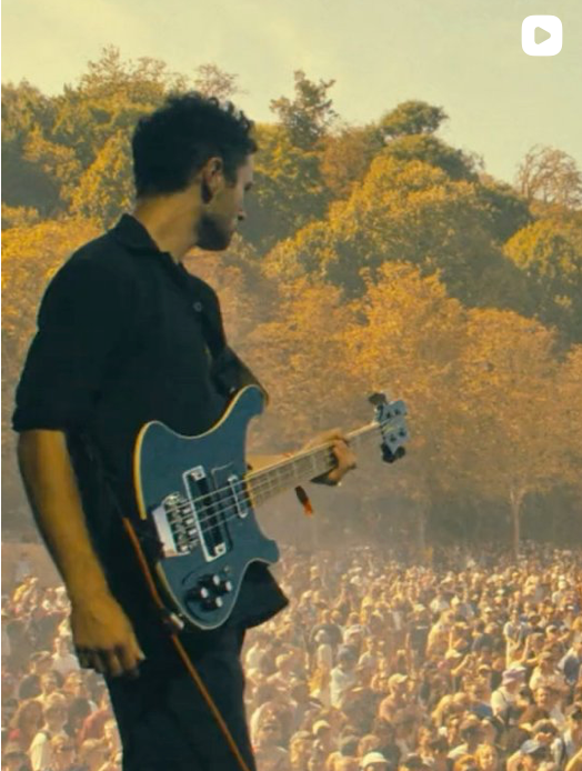 Bassist on stage looking out over a huge outdoor crowd