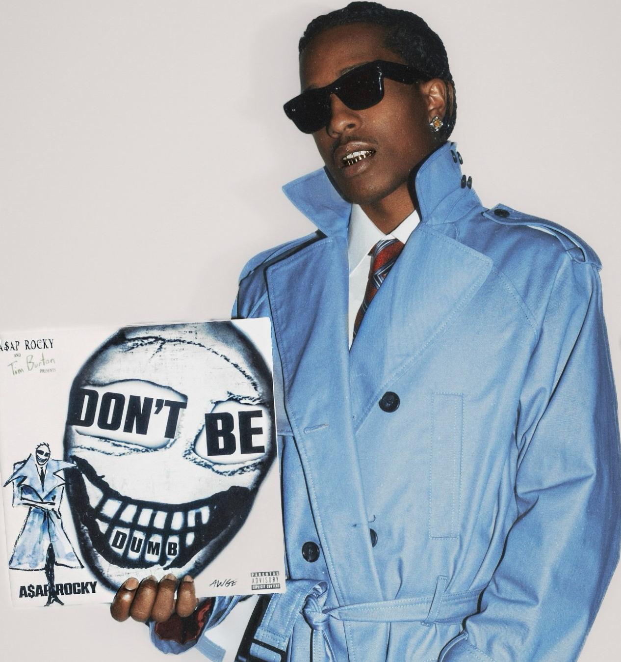 A$AP Rocky in a blue trench coat and sunglasses holding up the DON'T BE DUMB record
