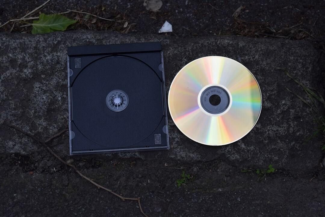 An empty CD case beside a loose CD on a dark stone surface
