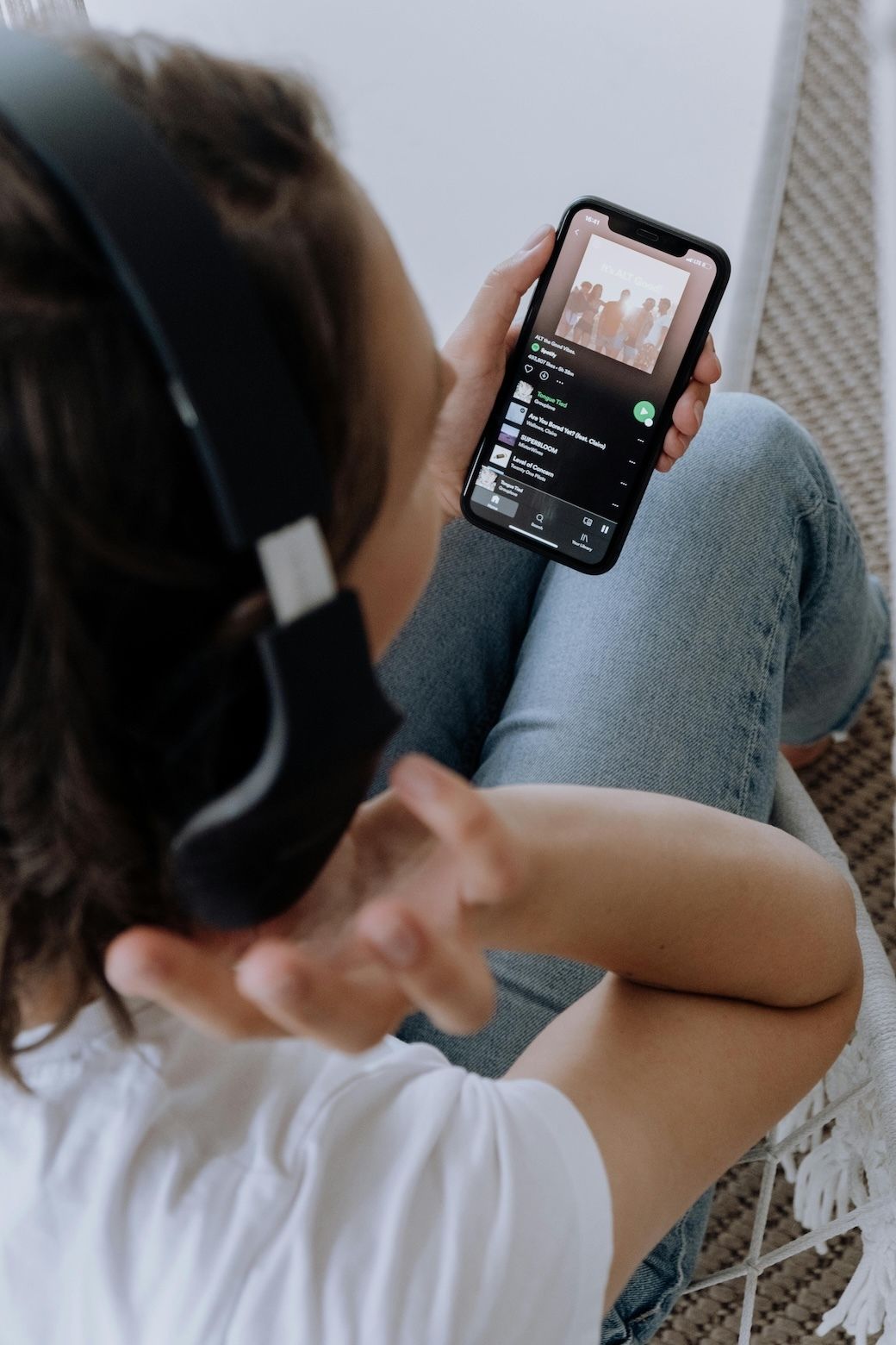Person in headphones scrolling a playlist on their phone