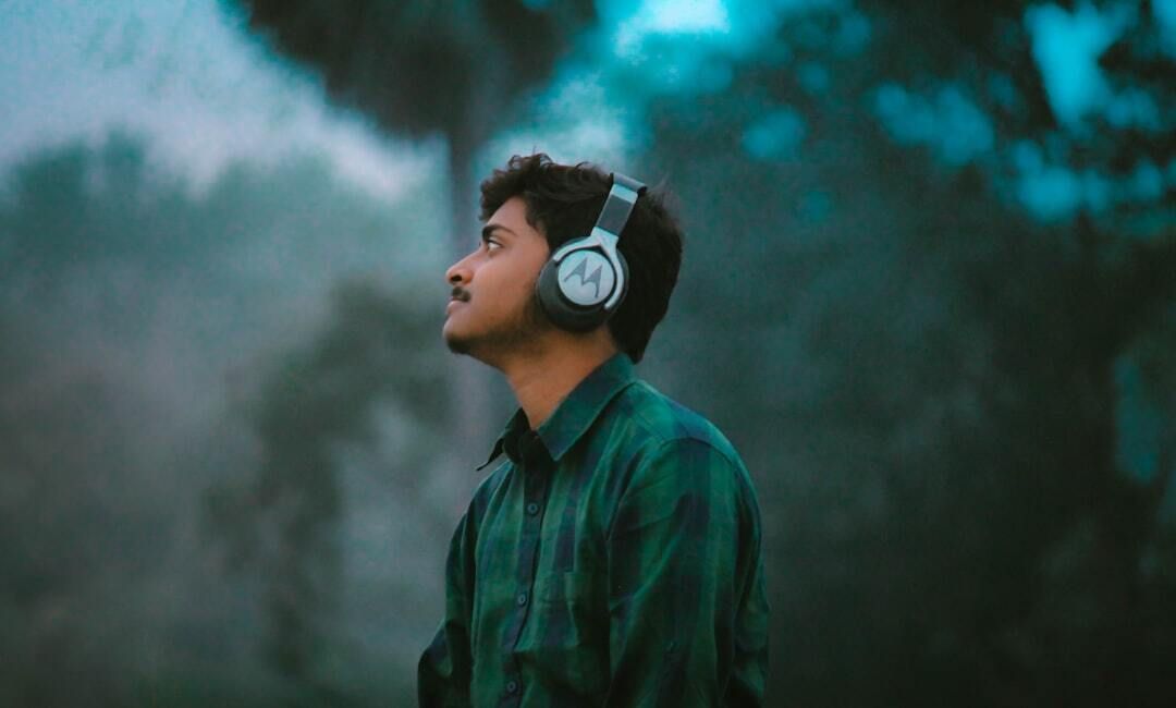 Man in headphones looking up at a misty sky