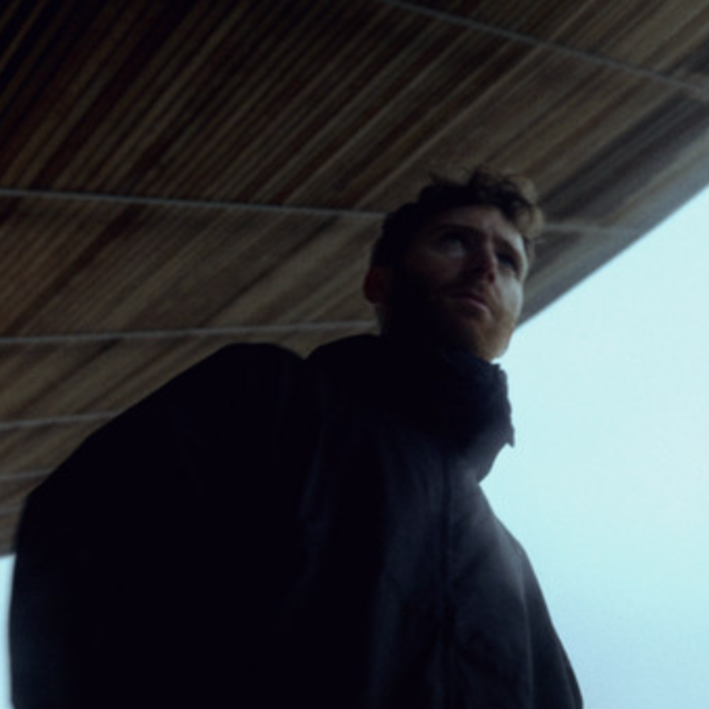 Silhouetted man in a dark jacket under a wooden roof