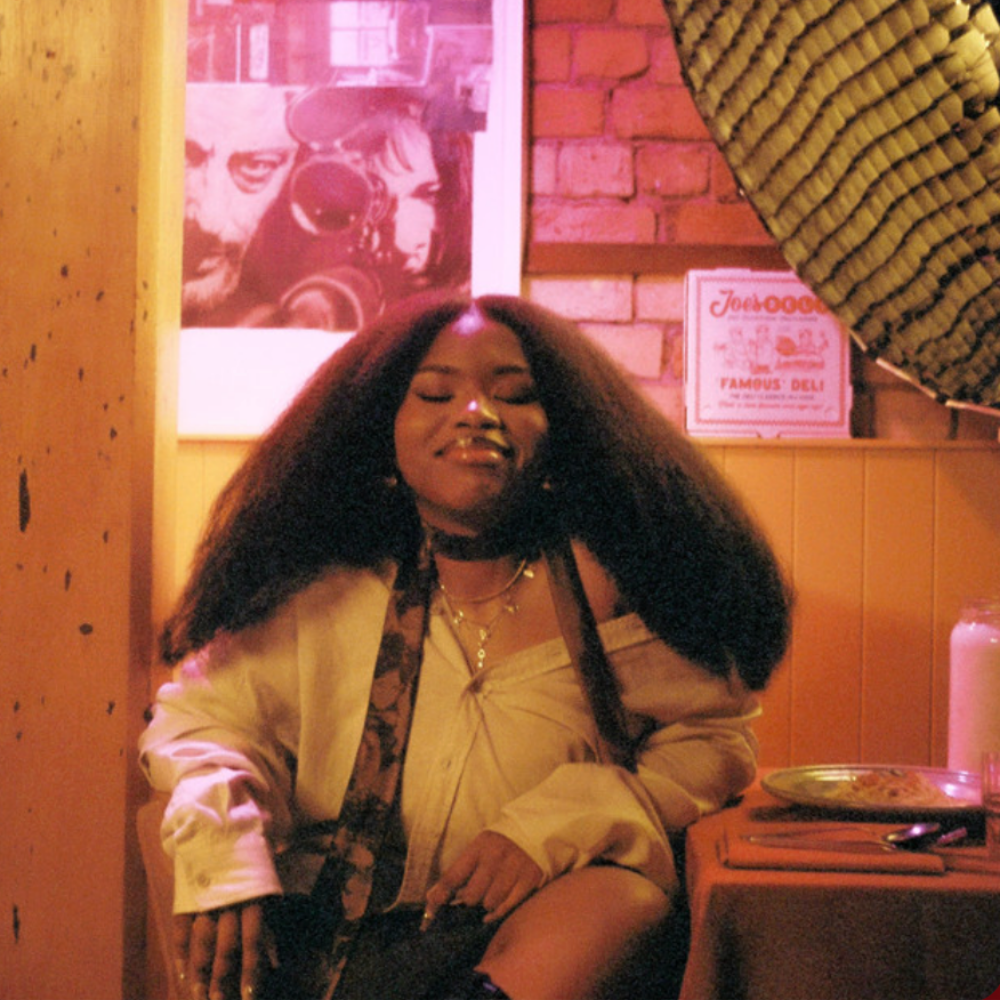Tusekah sitting in a warmly lit diner, eyes closed