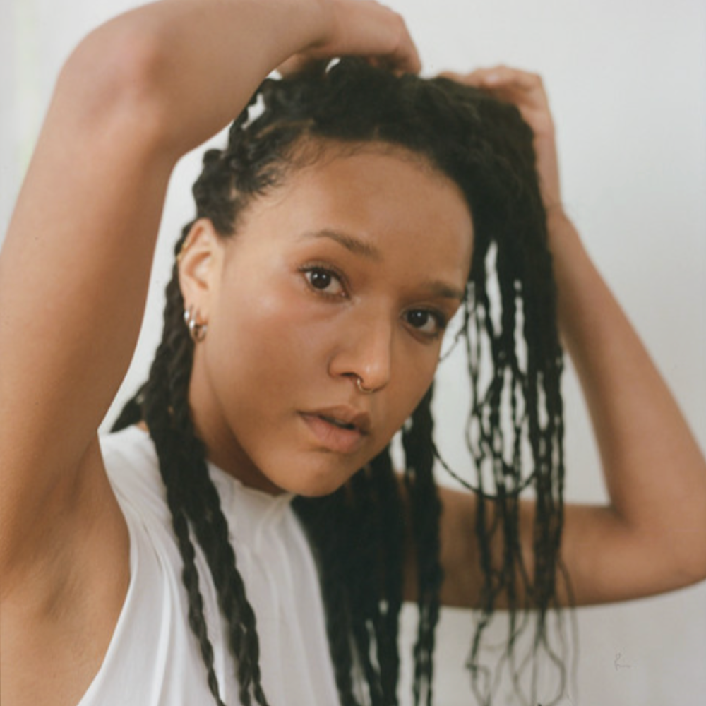 Becky Sikasa with long braids, hands in her hair