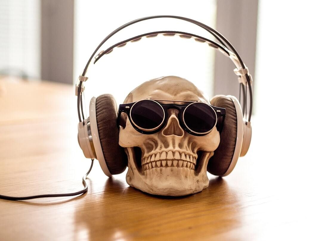 Skull wearing sunglasses and headphones on a wooden table