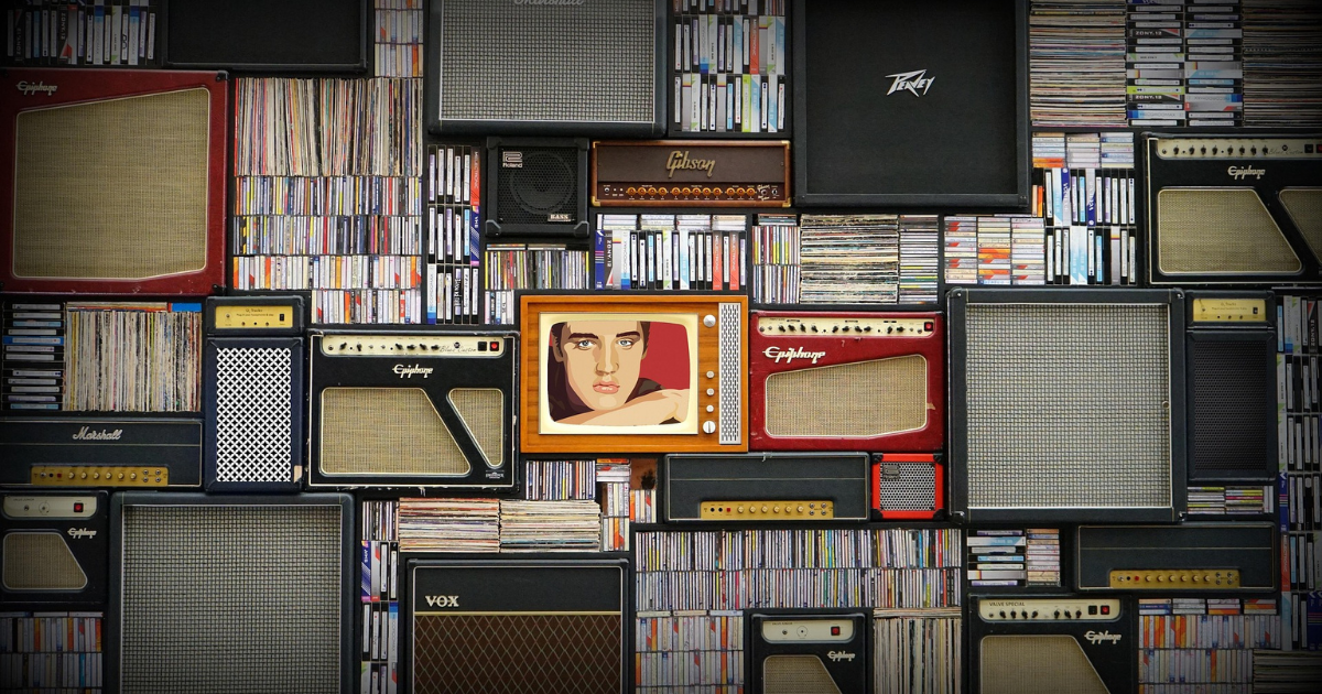 Wall of stacked guitar amps and shelves of records, with a pop-art portrait in the middle