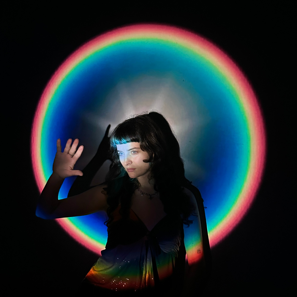 Woman in a dark room framed by a glowing rainbow ring of light