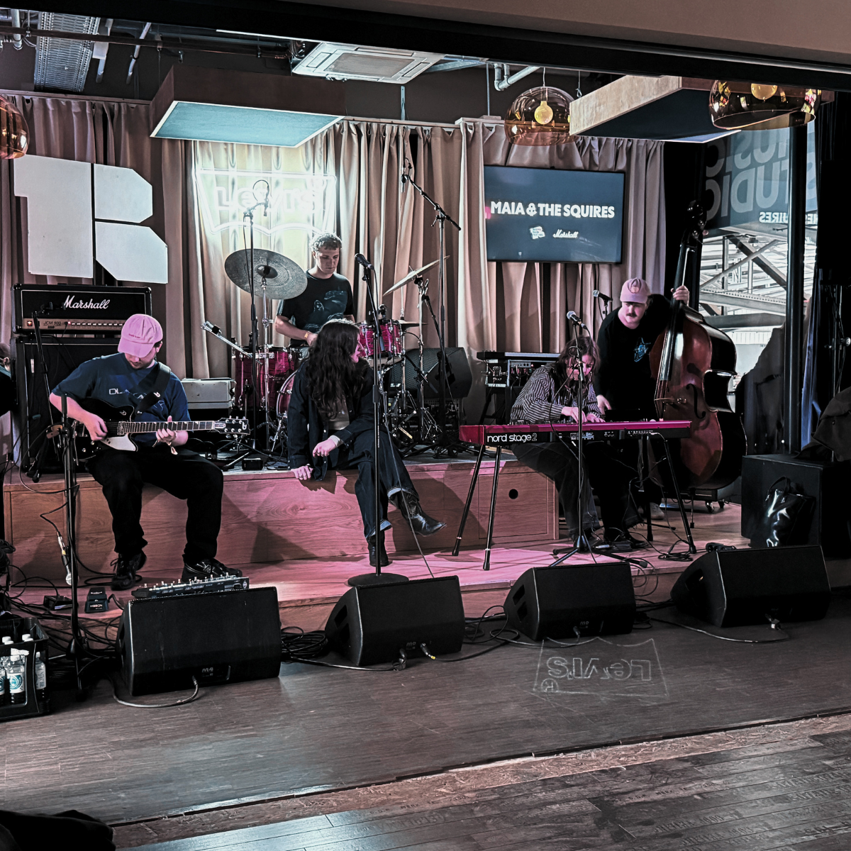 Mia and her band on stage while the screen behind them still shows Maia & The Squires