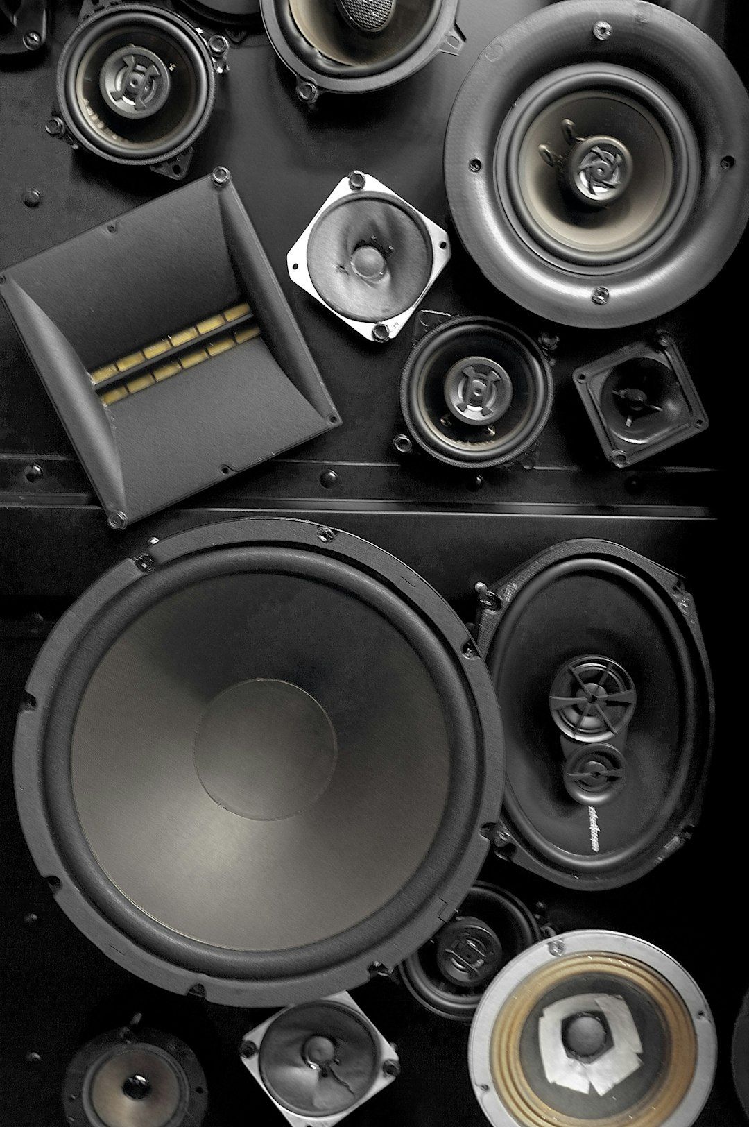 Wall of loudspeaker drivers of different sizes in black and white