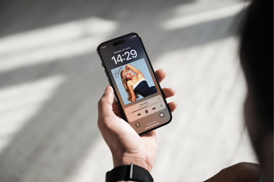 Hand holding a phone with a pop track playing on the lock screen