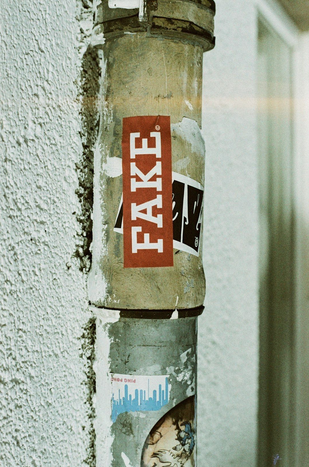 FAKE Urban street art sticker. Leica R7 (1994), Summilux-R 1.4 50mm (1983). Hi-Res analog scan by www.totallyinfocus.com – Lomochrome Metropolis