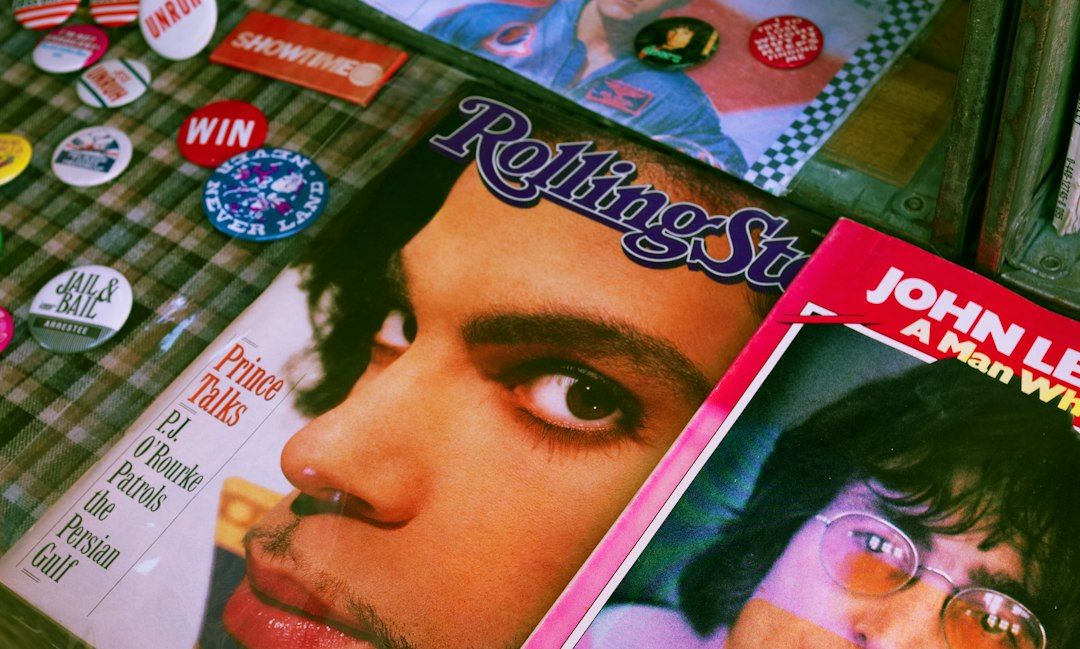 Old Rolling Stone magazines with Prince and John Lennon on the covers, beside a scatter of badges