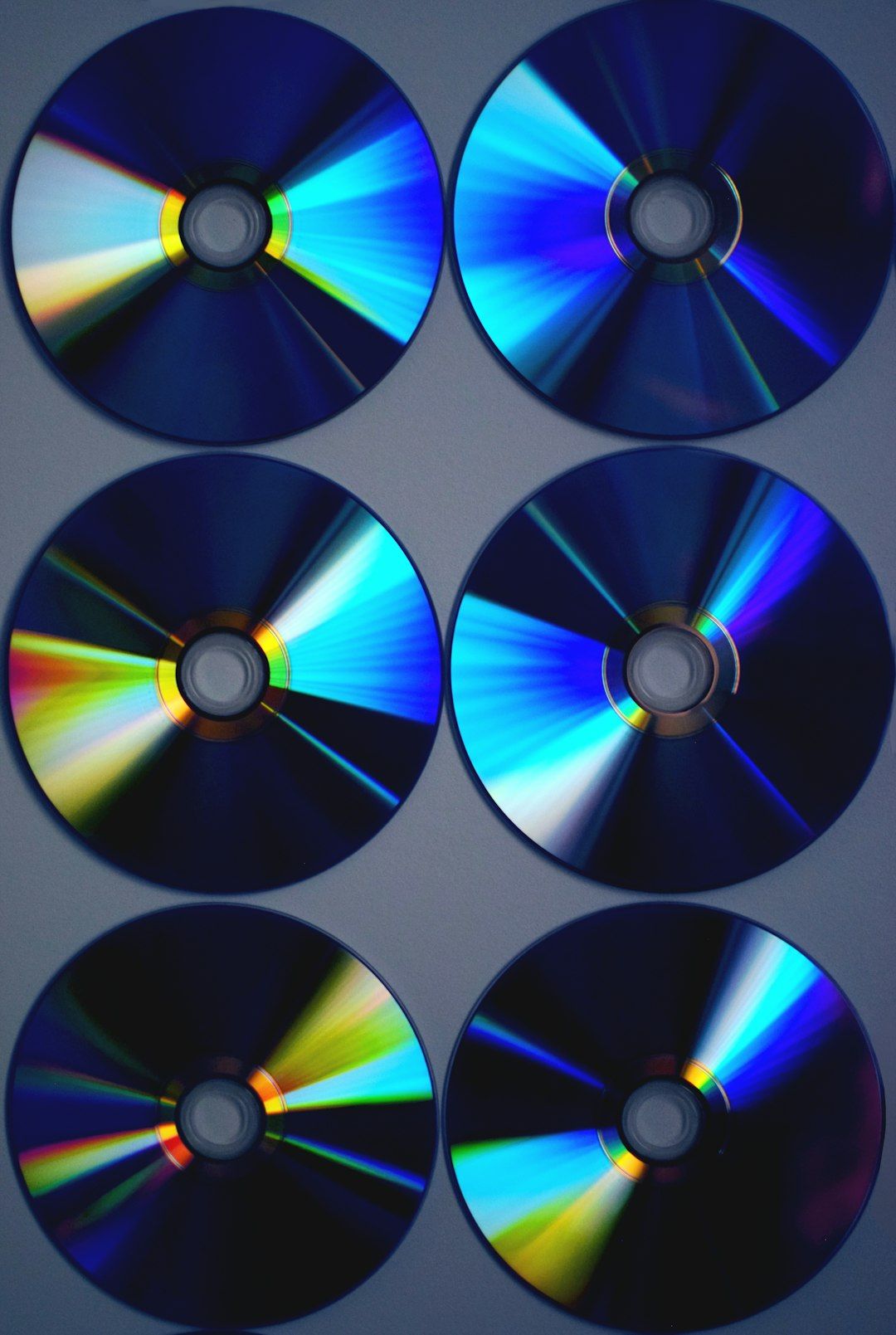 Six CDs laid out in a grid, their surfaces catching rainbow light