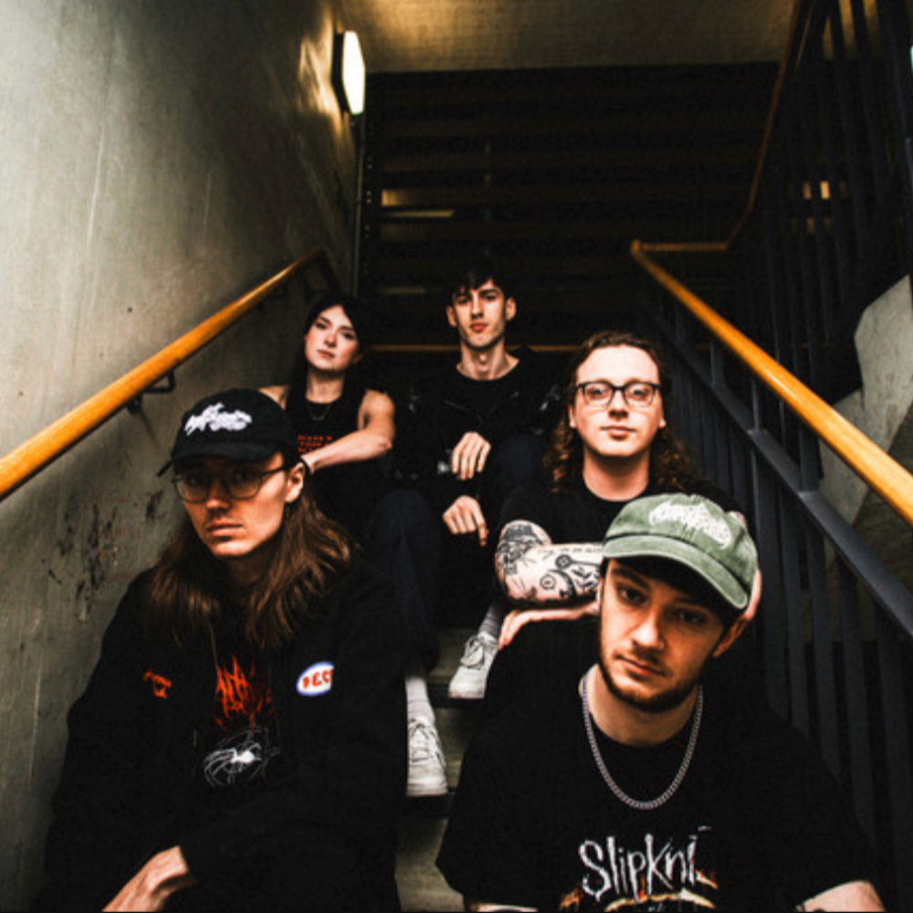 The metal band, five members sitting on a concrete stairwell