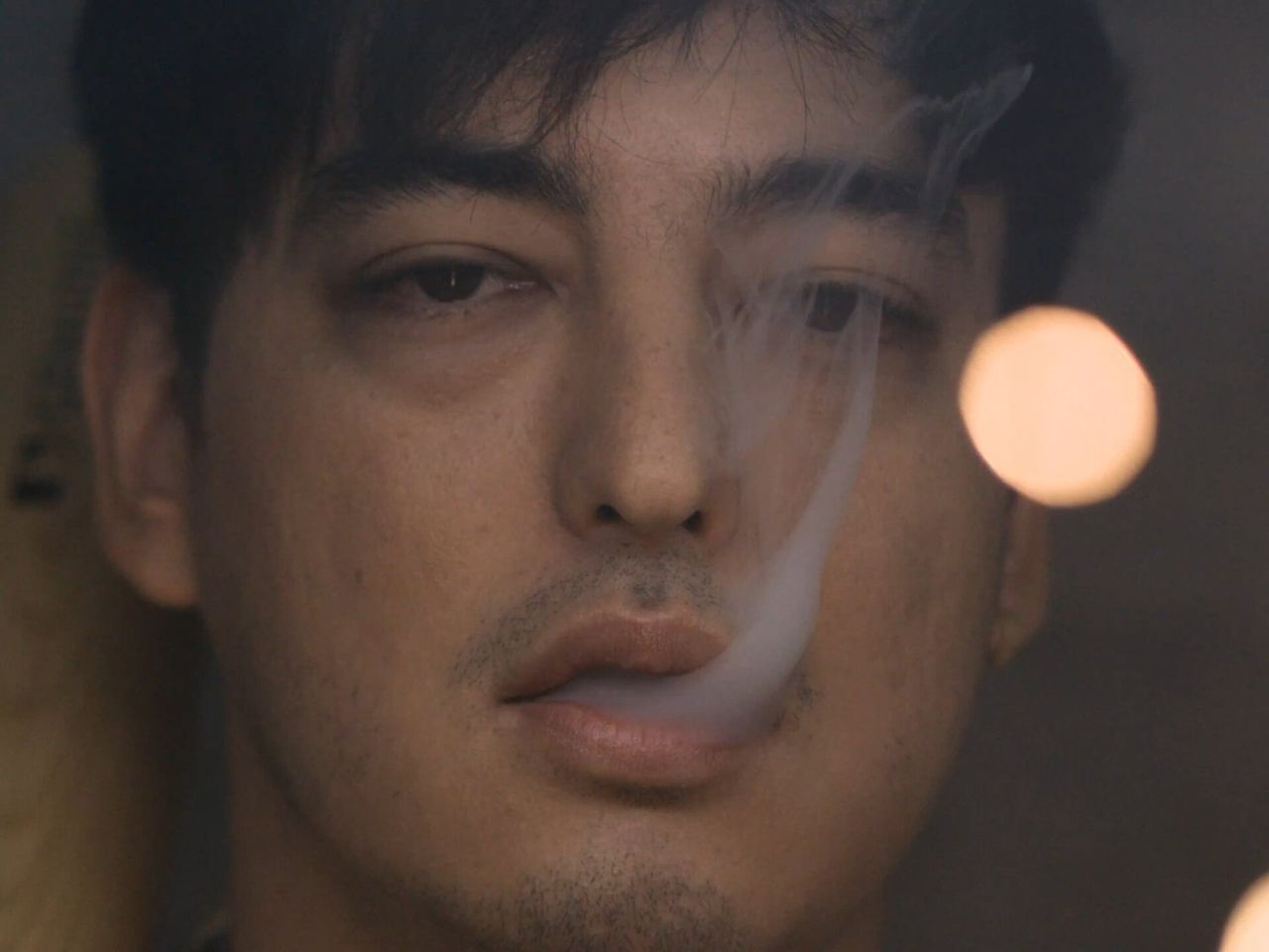 Close-up of Joji exhaling smoke