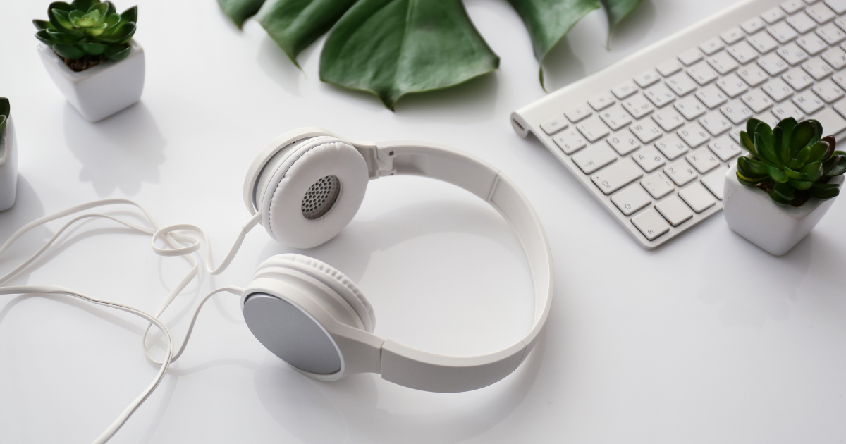 White headphones beside a keyboard and two small plants