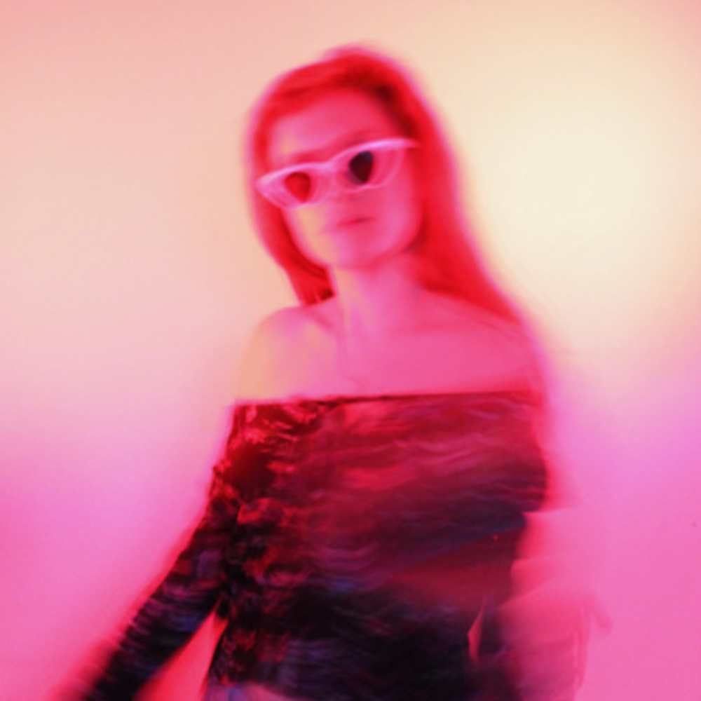 THEO in white sunglasses, photographed in blurred pink and red light
