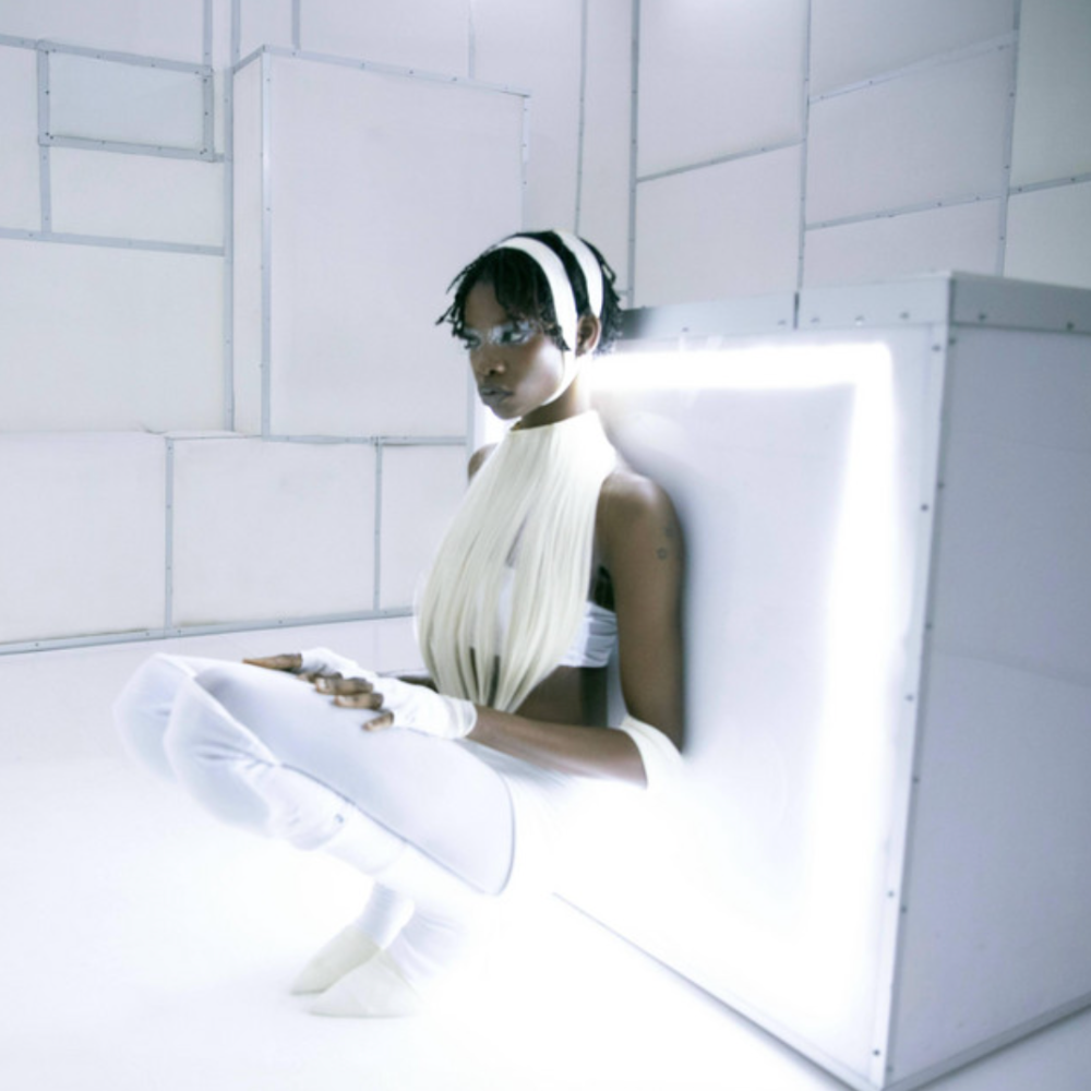 The genre-fluid pick seated against a glowing white box in a white room