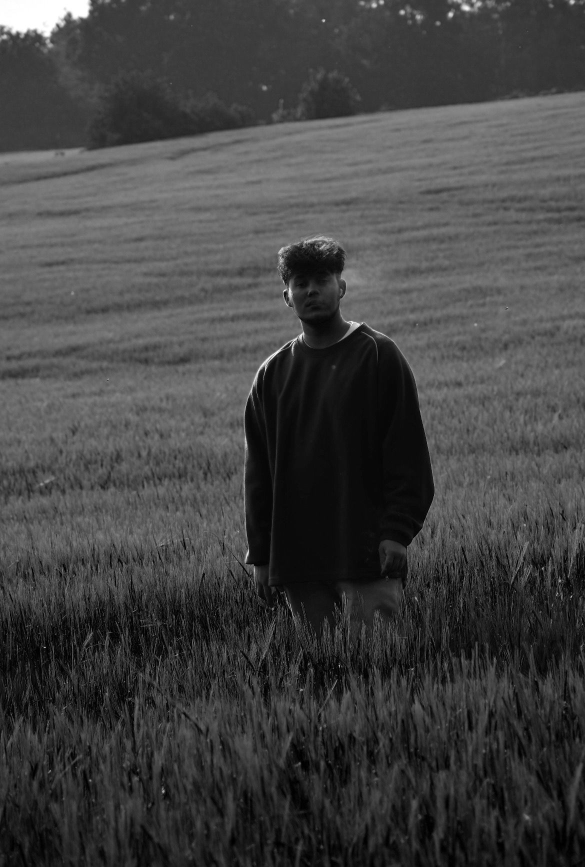 Black-and-white shot of David River standing in a field of long grass